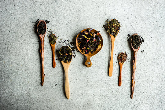 Overhead view of wooden spoons with assorted teas lined up on a table