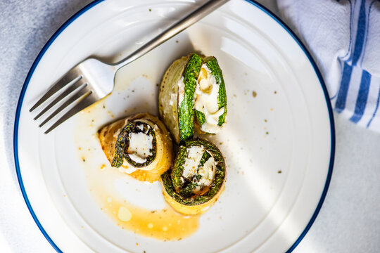 Overhead view of a plate of roasted courgette rolls filled with cream cheese