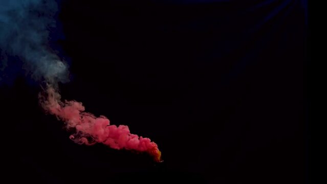 Colorful red smoke bomb or haze grenade blowing across screen for festival or celebrations on black background.