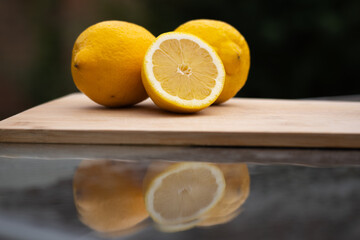 group of lemons on the wooden board, whole and cut, dark blurry background