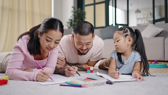 Asian parents draw pictures with daughter together on floor