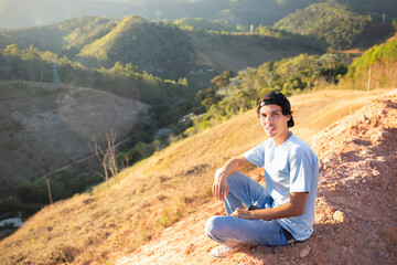 Portrait of a young man sitting on top of a mountain and enjoying nature.
