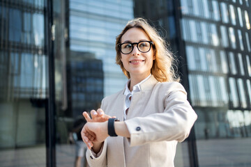 A business woman looks at the watch on her hand, goes to work in a new office.