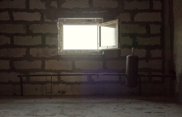A small bright window with an open sash inward. The light from the window illuminates the twilight of the service room, the roughly putty block walls and the metal structure of the pipe and tank.