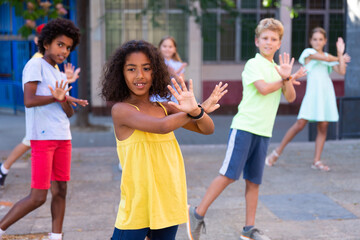 Obraz premium Positive african-american girl performing street dance with her friends outdoors.