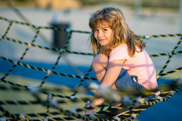 Child climbing the net. Little boy climbs up the ladder on the playground. Child climbs up the ladder. Little caucasian boy hanging on the monkey bar by his hand to exercise at outdoor playground.