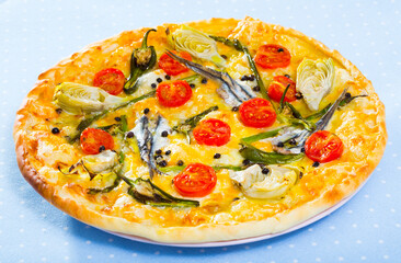 Pizza with sprat, artichokes, cheese and dried tomatoes on unleavened dough