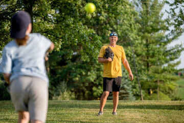 Marine veteran at home with family playing catch and teaching how to bunt a softball.