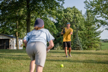Marine veteran at home with family playing catch and teaching how to bunt a softball.