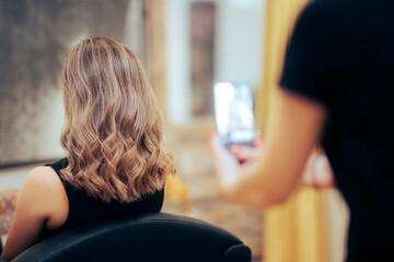 Hairdresser Taking a Picture After Coloring Hair Job. Proud hairstylist taking smartphone photos of...