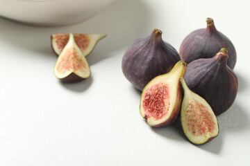 Whole and cut tasty fresh figs on white table