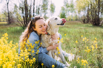 Young beautiful woman and her golden retriever dog having fun in summer