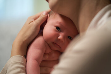 Newborn baby. mother holds baby in her arms holding him close to her breast. baby looks at camera