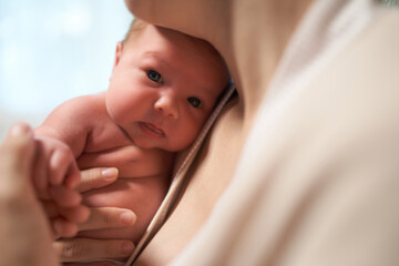 Newborn baby. mother holds baby in her arms holding him close to her breast. baby looks at camera