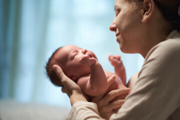 Newborn baby. mother holding baby in her arms flirting with him.