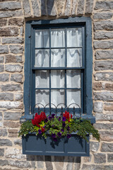 Fototapeta na wymiar Blue framed window on a stone wall with flower box
