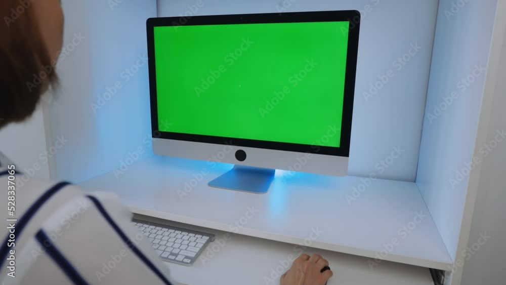 Poster brunette sitting at the workplace display computer with green screen working at home office