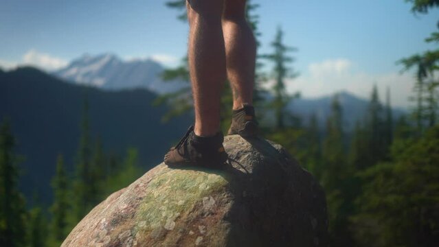 Caucasian man hiking with toe shoes steps on rocky viewpoint, close up