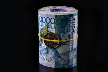 One million Kazakhstani tenge in a folded bundle of banknotes of 10,000 tenge on a black background