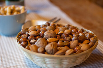 Close up of a big bowl of mixed nuts on table. Focus on the walnut in the middle of the bowl
