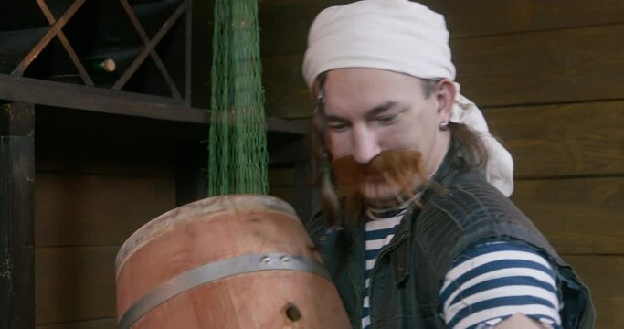 Oenophile kisses oak barrel with aged wine, rejoices in stock. Man warehouse worker in traditional winery in basement arranges drinks. Authentic traditional wine production. Sailor supplies alcohol 