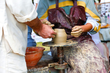 Defocus woman potter teaching the art of pot making. Women working on potters wheel making clay objects in pottery workshop. Master class on modeling of clay. Out of focus