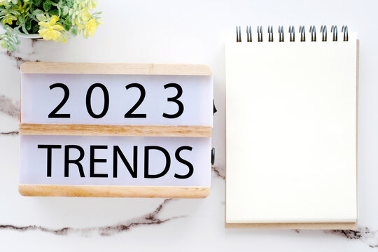 2023 trends on wooden box, Blank paper notebook and pen on white table background, new year business trend mock up, template, copy space for text