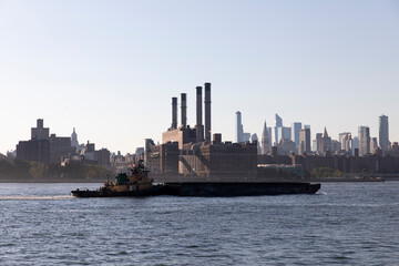 Naklejka premium Tugboat barge on East River with view of power plant in Manhattan.