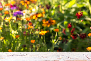 Old empty table top against abstract blur floral background in sunny summer day