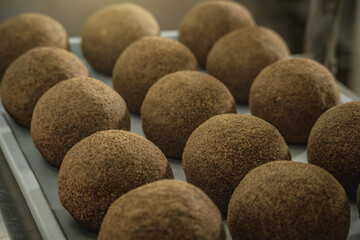 Cheese balls sprinkled with black pepper lie in a row . The production process of spicy Belper knolle cheese