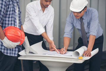 Civil engineer teams meeting working together wear worker helmets hardhat on construction site in modern city. Foreman industry project manager engineer teamwork. Asian industry professional team