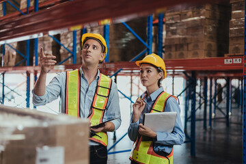 Warehouse Workers Checking Stock with digital Tablet in Logistic center. Caucasian worker wearing hard hat and safety vests to talking about shipment in storehouse, Working in Distribution Center.