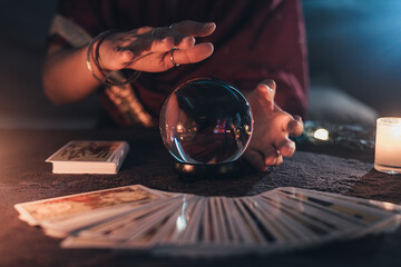 Fortune teller with illuminated crystal ball and tarot cards to prediction future. Hands of...