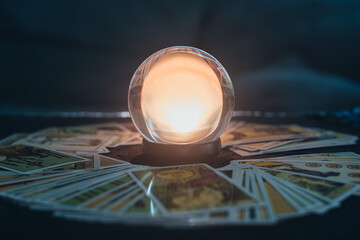 Fortune teller with illuminated crystal ball and tarot cards to prediction future. Hands of astrologists reading future and destiny. Horoscope and forecasting concept.