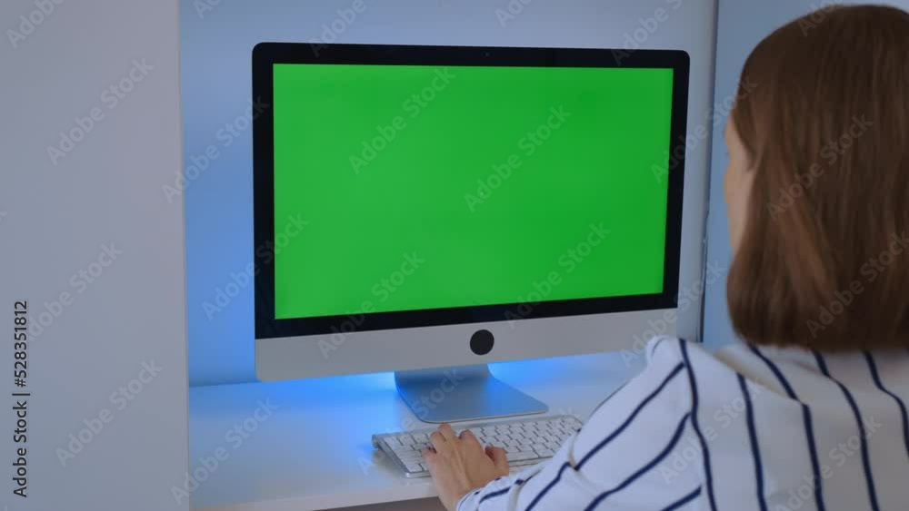 Poster side view woman sitting at the workplace display computer with green screen working at home office