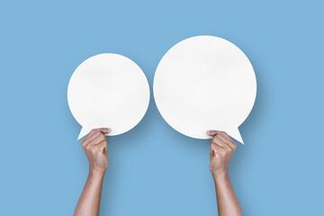 hand holding round white paper balloons speech bubbles isolated on light blue background