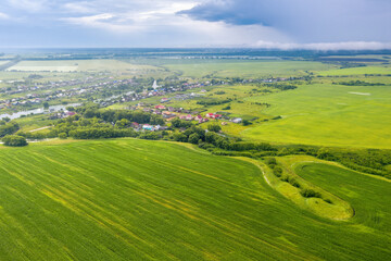 Fototapeta premium Russian rural landscape. Aerial view of Alekseevka village and surrounding fields on rainy summer day. Penza Oblast, Russia.