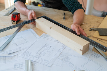Carpenter measures wooden planks in the workshop.