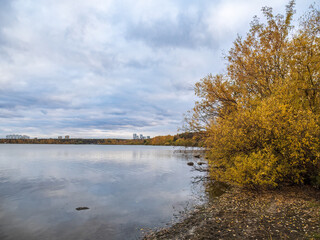 Autumn lake with trees on the shores. Reflection of blue sky with clouds in water.