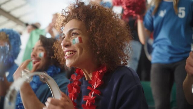 Sport Stadium Soccer Match: Portrait of Beautiful Bi Racial Fan Girl with Italian Flag Painted Face Cheering Team to Win, Beating Tambourine. Crowd Celebrate Goal, Championship Victory. Slow Motion