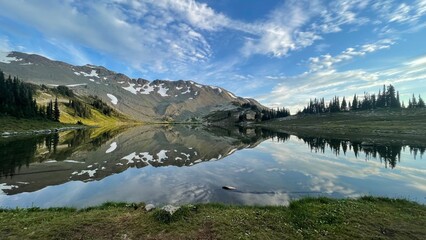Reflection of mountain in a lake like glass. Blue sky and clouds.