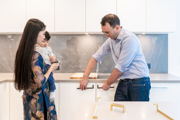 Male interior designer with female and child family customer holding kitchen cabinet handles in configuration to make a selection for their home interior decor.