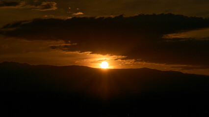 Fototapeta na wymiar Sunset, sun hiding behind some mountains