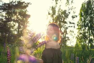 An attractive woman in a field with a summer bouquet of wildflowers Lupinus. Front view.
