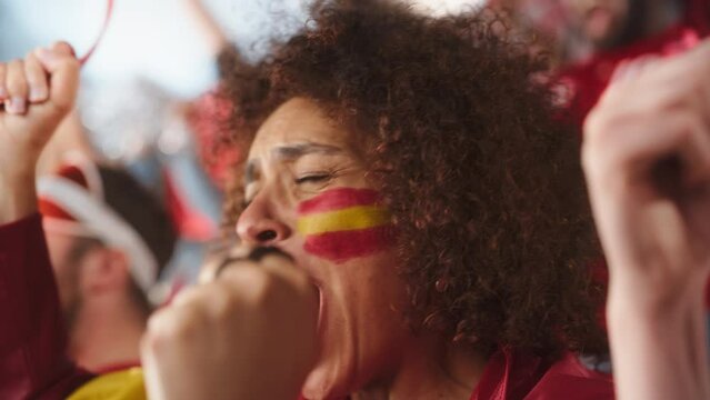 Sport Stadium Soccer Match: Portrait of Beautiful Bi Racial Fan Girl with Spanish Flag Painted Face Cheering Team to Win, Beating Tambourine. Crowd Celebrate Goal, Championship Victory. Slow Motion