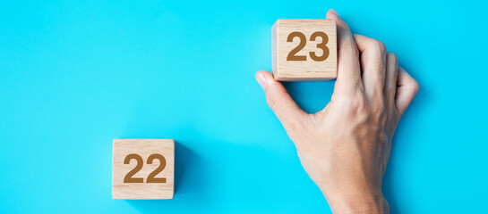 hand holding wooden cube block with 2023 text on blue background. Resolution, plan, review, goal,...