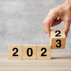 hand flipping block 2022 to 2023 text on table. Resolution, strategy, plan, goal, motivation,...