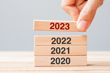 2023 block over 2022 and 2021 wooden building on table background. Business planning, Risk...