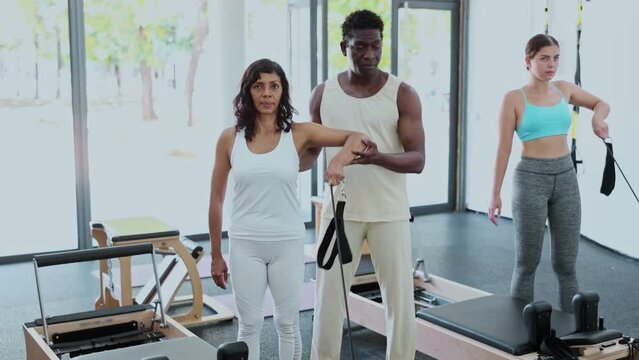 African american man coach training woman in pilates workout in gym. High quality 4k footage