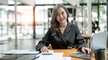 Young asian beautiful and charming busineswoman smiling and working on laptop computer at office.